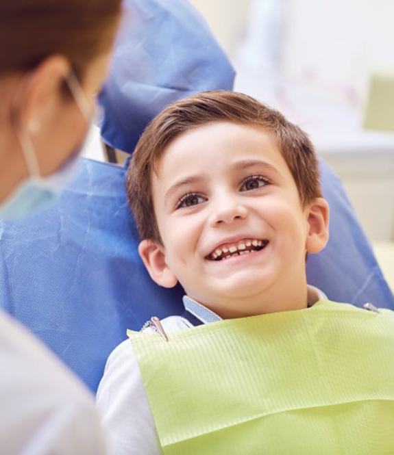 little boy smiling at his dentist before getting dental sealants in Grand Prairie 