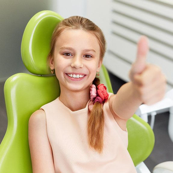 Young girl giving thumbs up at dentist's office