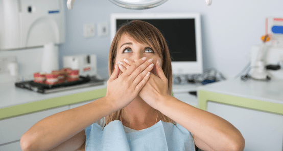 Woman in need of sedation dentistry covering mouth