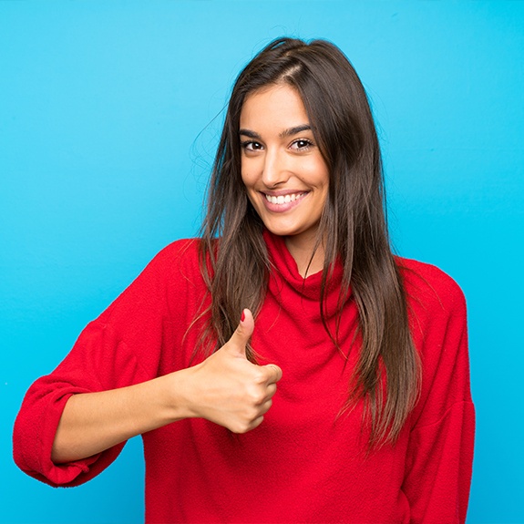 Woman giving thumbs up after a dental checkup