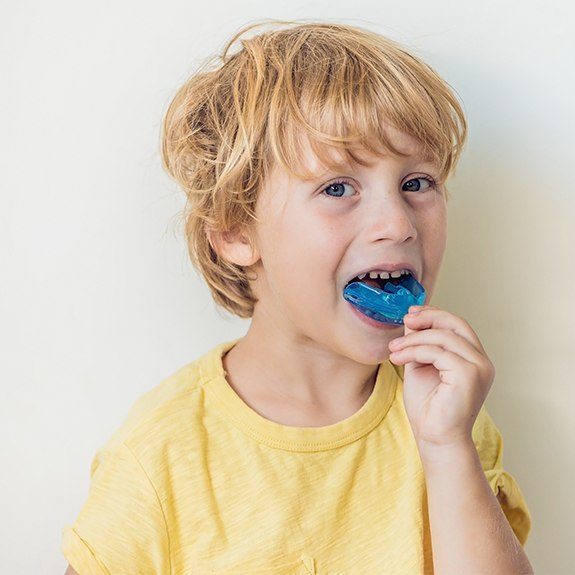 Young boy placing blue athletic mouthguard