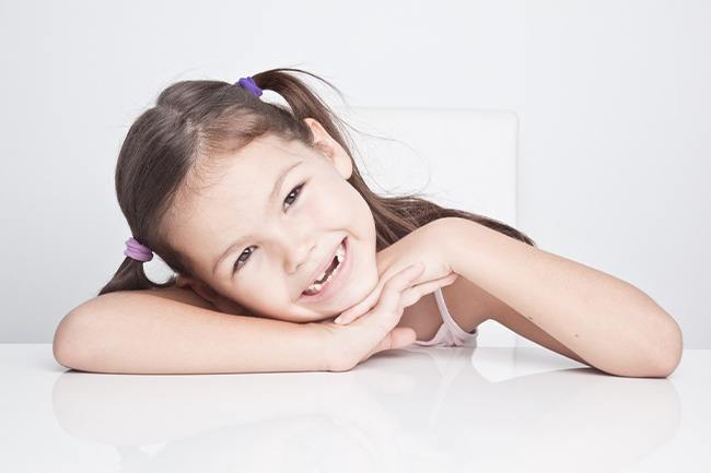 A little girl wearing pigtails and showing off her smile in Grand Prairie