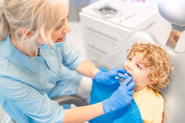 A dentist checking a young boy’s mouth during an appointment in Grand Prairie