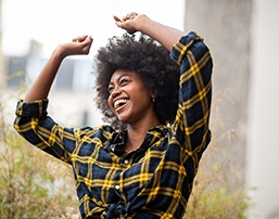 Woman smiling with her hands up outside