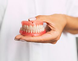 dentist holding removable dentures 