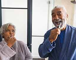 Couple smiling while brushing teeth in bathroom