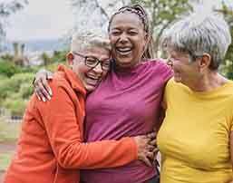 Friends smiling while hugging outside