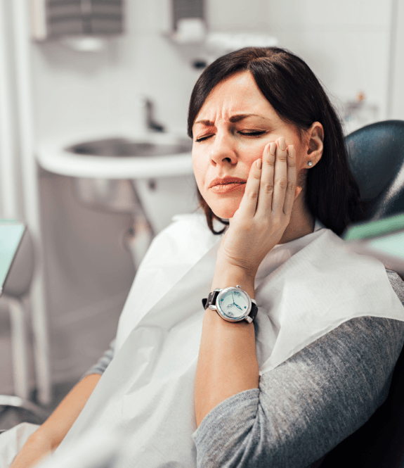 Woman in pain holding cheek during emergency dentistry appointment
