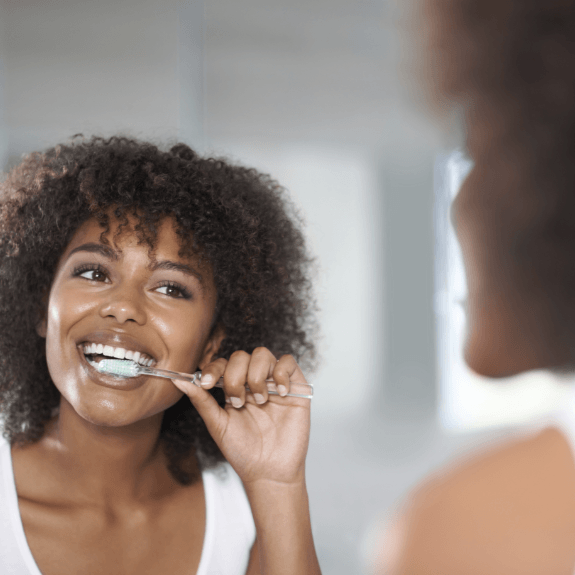 Woman brushing teeth to prevent a dental emergency