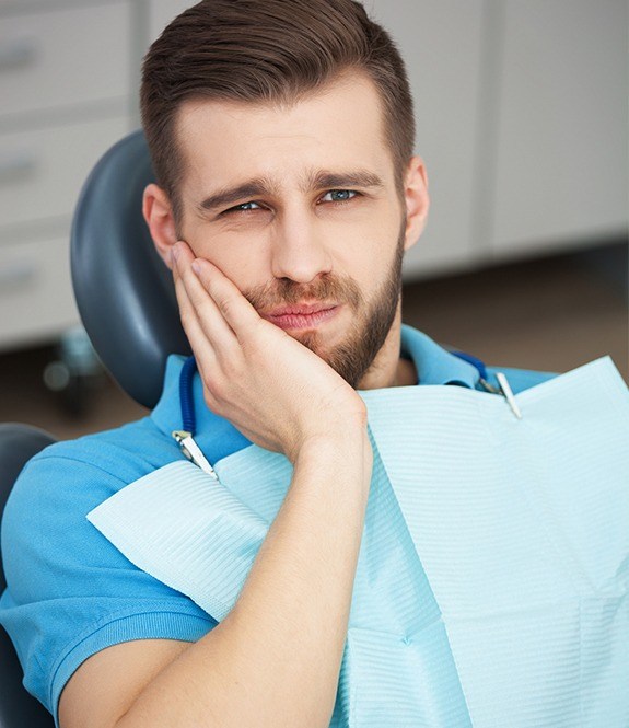 Man in need of tooth extraction holding cheek