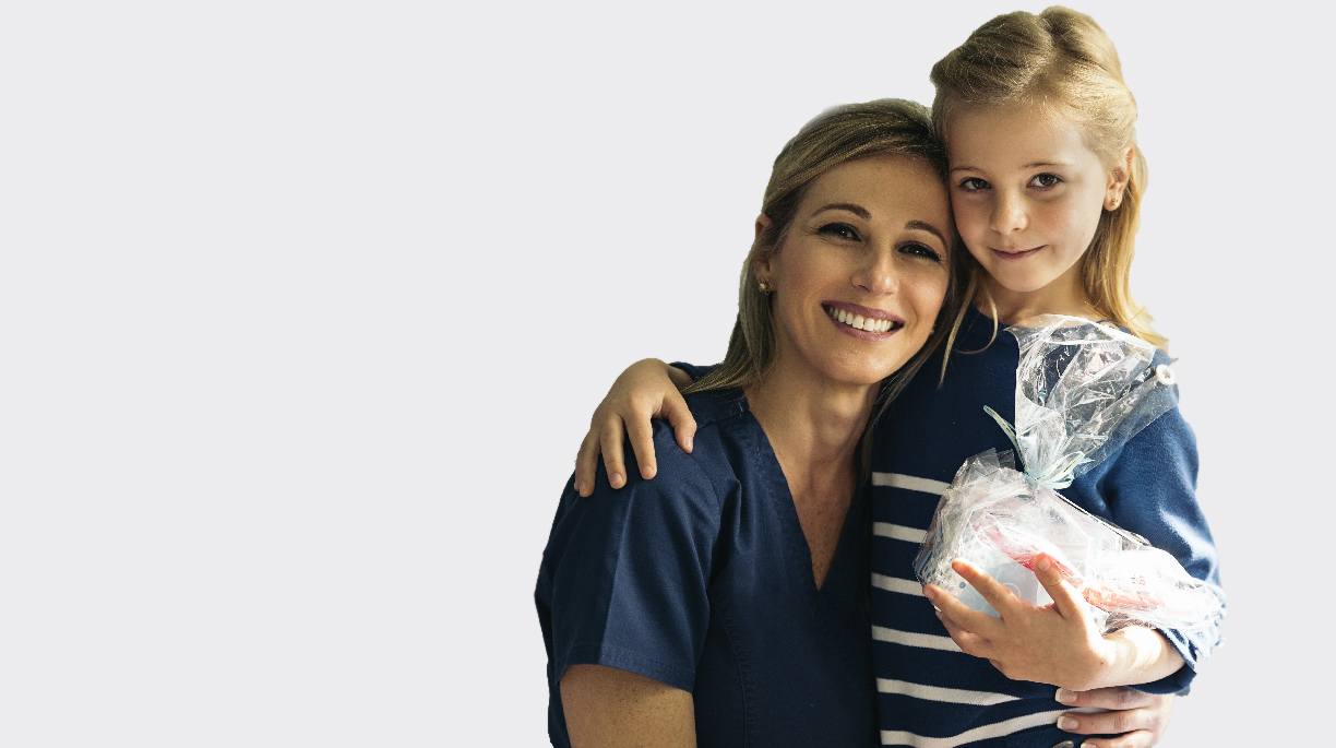 Smiling mother and daughter with oral hygiene gift basket