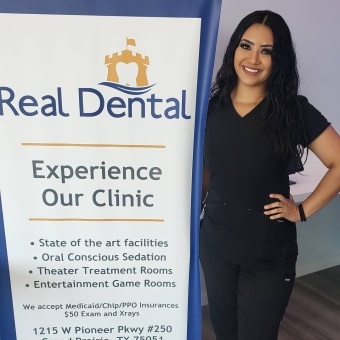 Team member standing next to Real Dental display sign