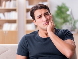 Man in need of emergency dentistry holding cheek