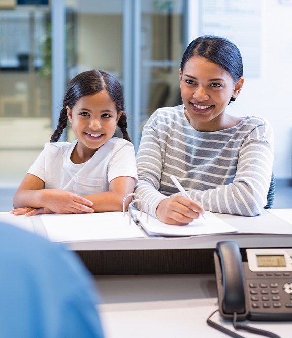 Mother and daughter filling out dental insurance forms at dental office