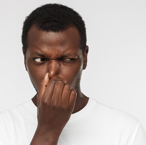 Man covering his nose due to bad breath