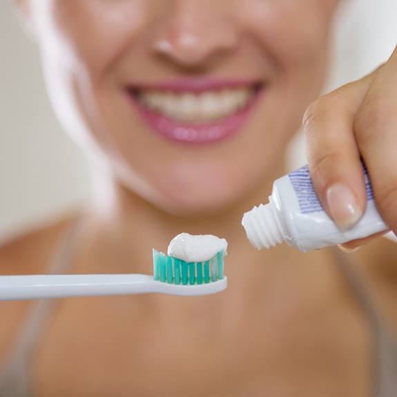 Woman placing toothpaste on toothbrush