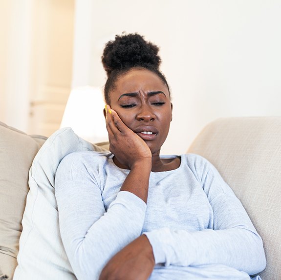 Woman with toothache sitting on couch