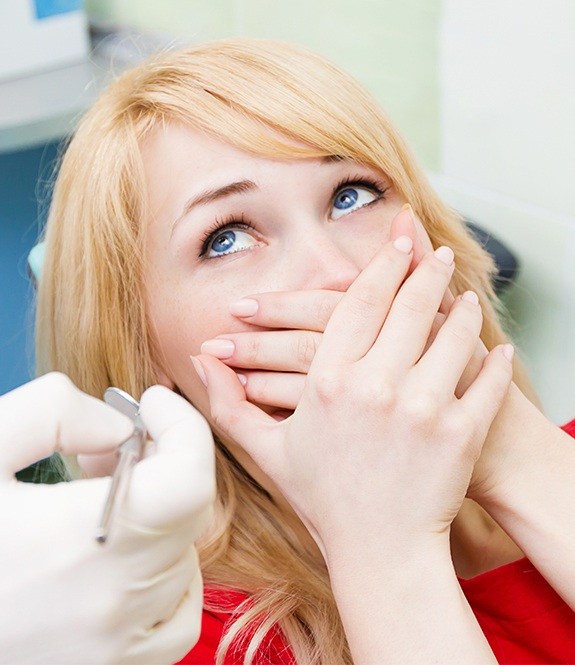 Fearful patient in need of sedation dentistry covering her mouth