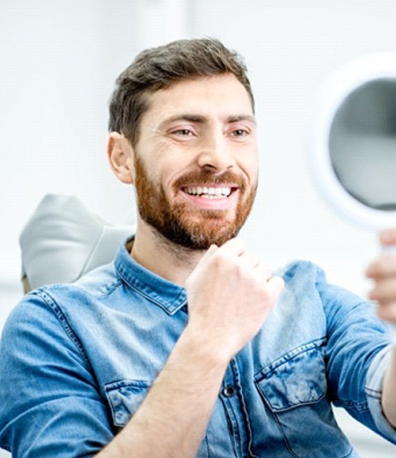 man admiring his smile after getting tooth-colored fillings in Grand Prairie