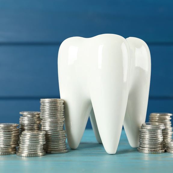 A large ceramic tooth surrounded by silver coins