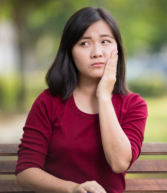 Young woman in need of wisdom tooth extraction holding jaw