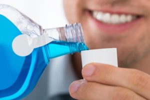 WOman pouring blue mouthwash into cup