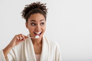Woman with curly hair brushing her teeth