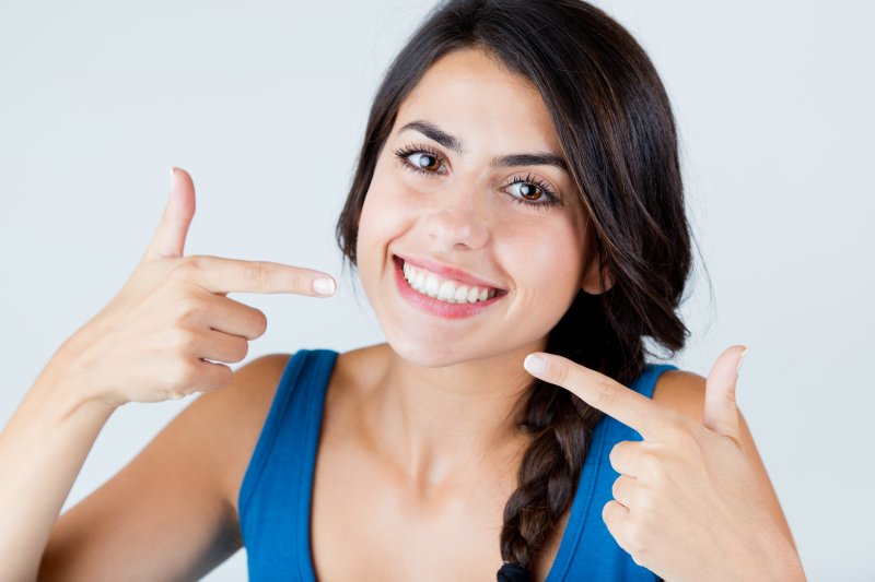 young woman pointing to her smile
