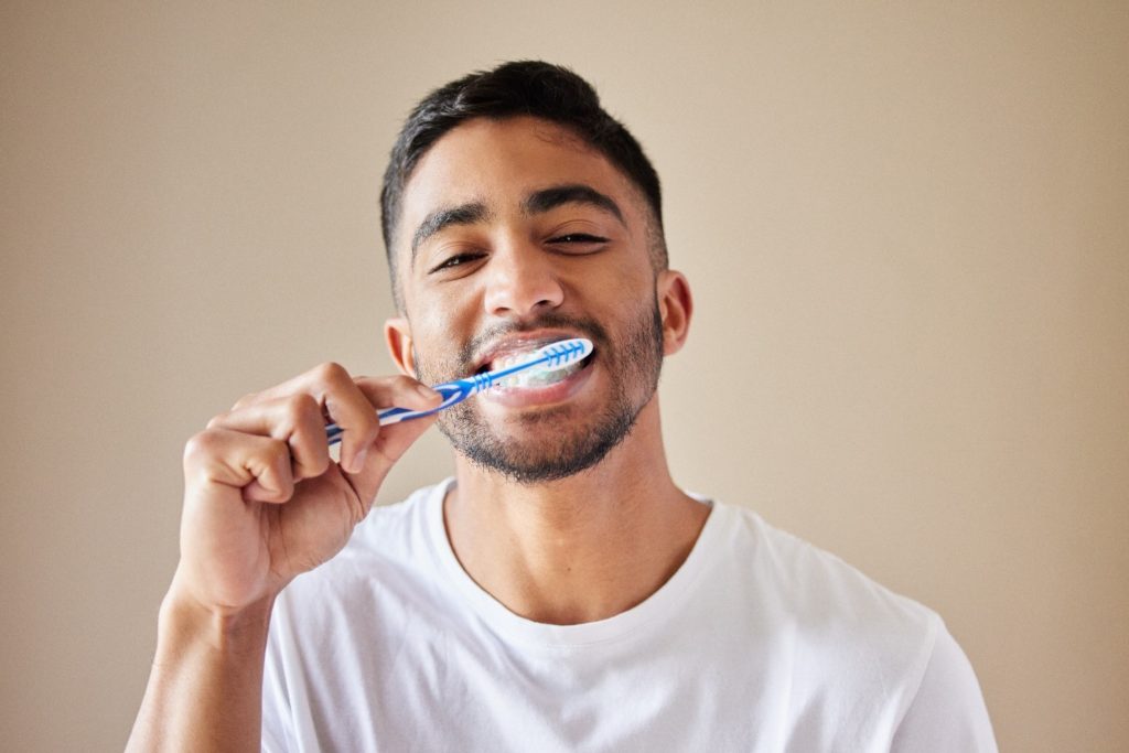 person smiling while brushing teeth