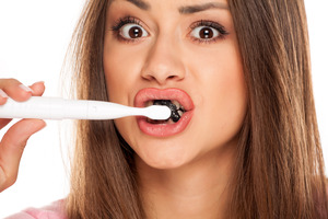 Someone brushing with charcoal toothpaste