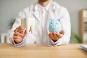 Man holding a tooth model and piggy bank
